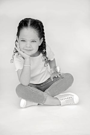 Three black and white photos show a child sitting cross-legged in a white shirt while making playful expressions.