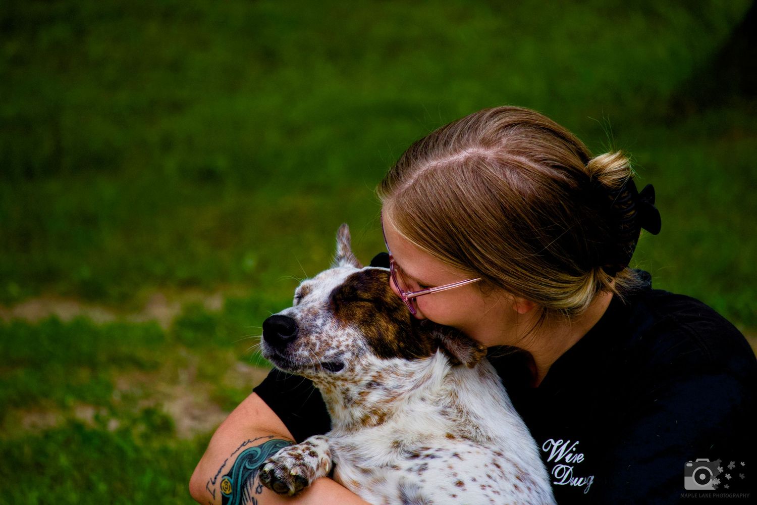 A spotted dog receiving affection and kisses outdoors.