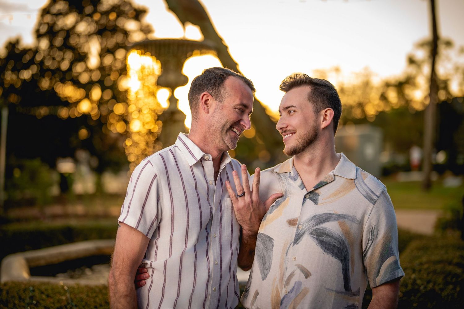 Two people share a joyful moment together outdoors during golden hour sunset in a park setting.