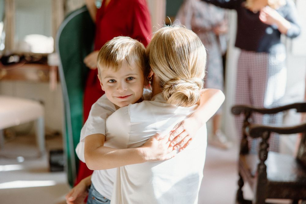 A tender embrace captured during wedding preparations in a sun-lit room.