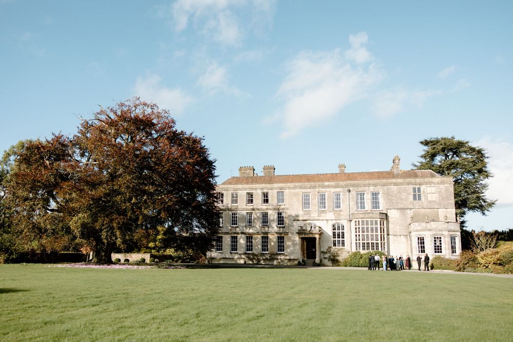 A stately countryside mansion with manicured lawns serves as an elegant wedding venue.