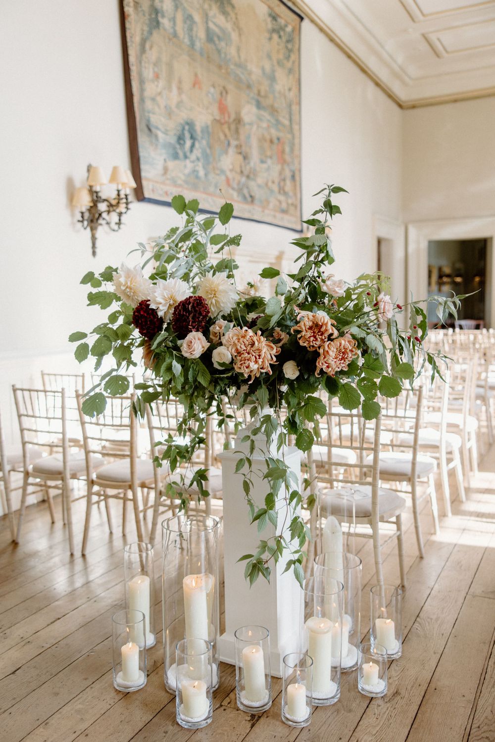 Elegant floral centerpiece with blush flowers and greenery surrounded by glass candle holders.