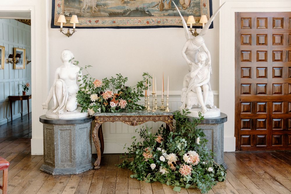 Elegant wedding decor featuring white statues and pink floral arrangements in classic interior.