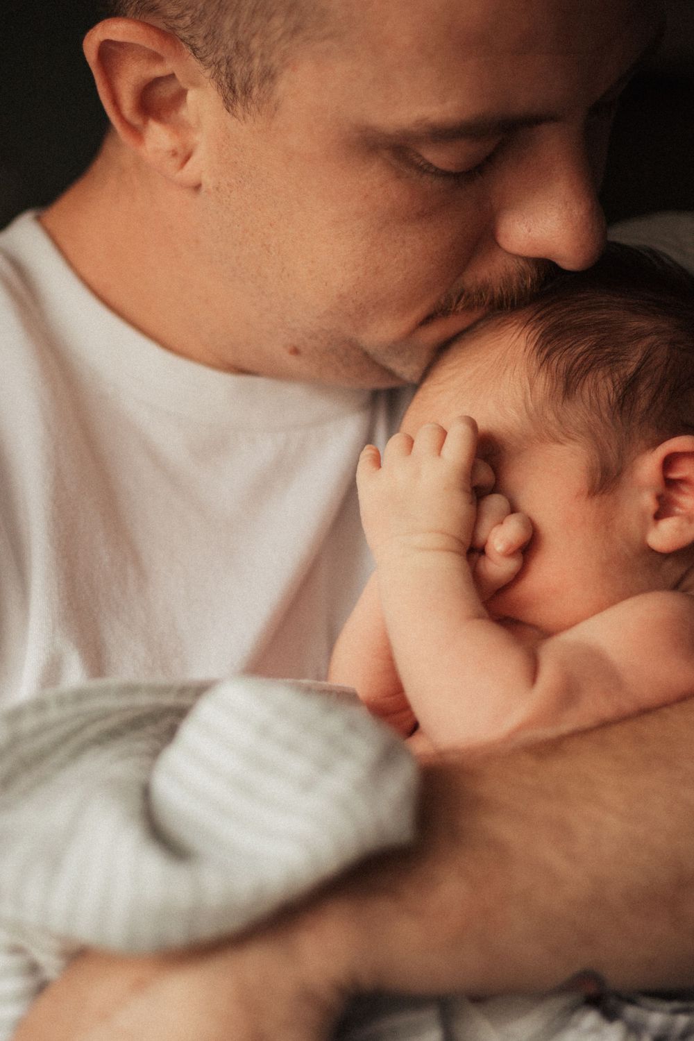 An intimate bonding moment between parent and baby in soft lighting.