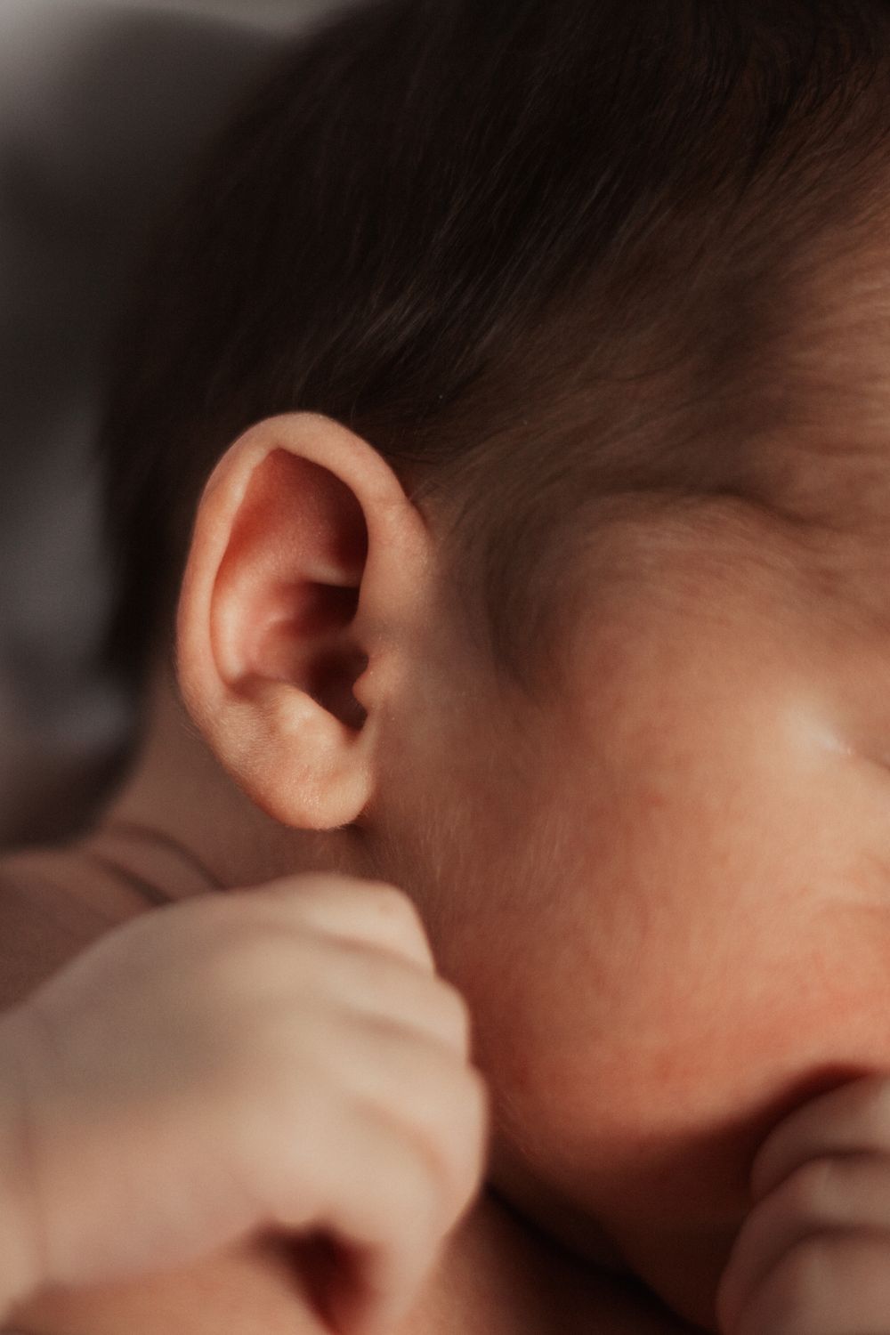 Close-up detail of a baby's ear and soft skin.