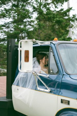 A vintage blue and white truck parked outdoors with delicate flowing tulle fabric visible through the window.