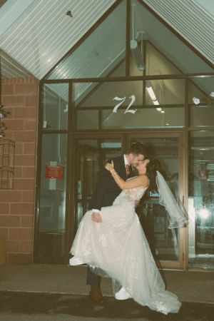Newlywed couple in romantic dance pose outside building number 72 at night.