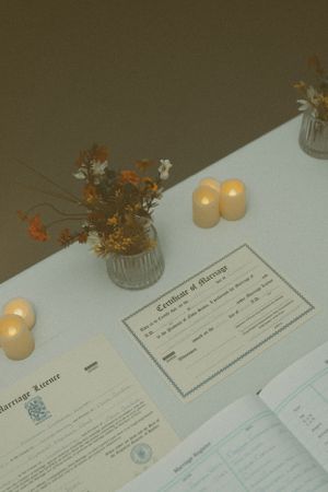 Legal documents arranged on a white surface with glowing candles and dried flowers in a glass vase creating an elegant atmosphere.