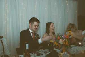 Wedding reception scene with twinkle lights and floral centerpieces at a dining table.