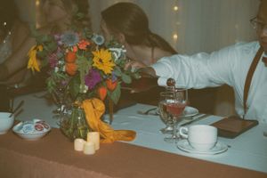 A table setting with colorful floral centerpiece, wine glasses, and cups at a reception.