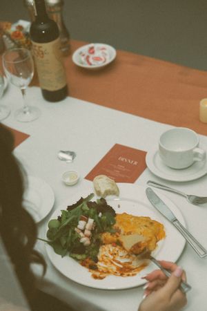 Elegant plated meal with salad and wine glass at wedding reception.