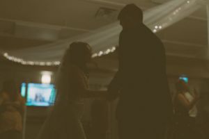 Silhouette of couple dancing at dimly lit wedding reception.