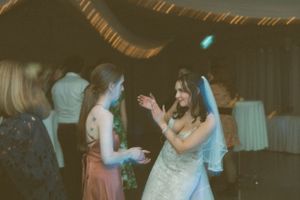 People dancing and celebrating at a wedding reception with vintage-style lighting and decor.