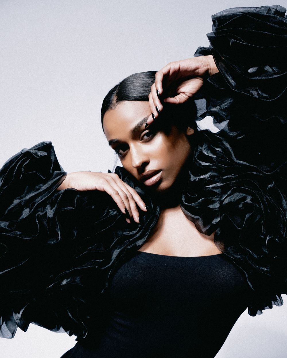 High fashion beauty portrait with black ruffled jacket and sleek styling.