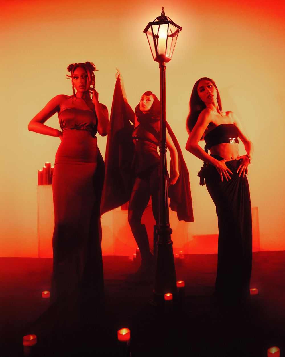 Three silhouettes pose dramatically under red lighting with vintage street lamp in theatrical scene.