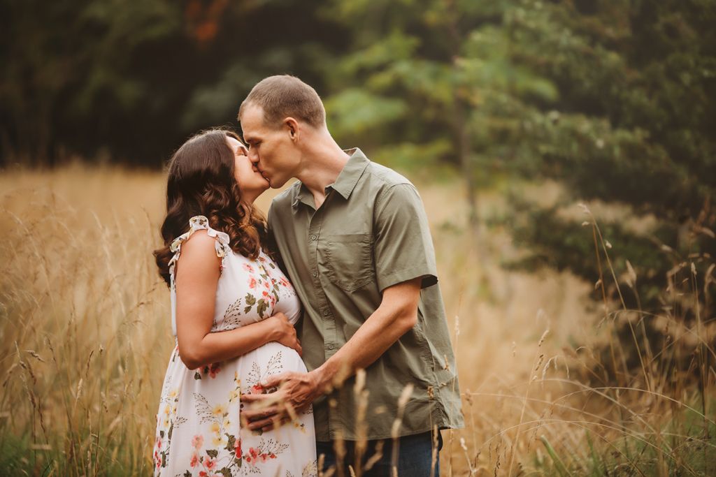 A couple shares an intimate moment in a golden field during sunset.