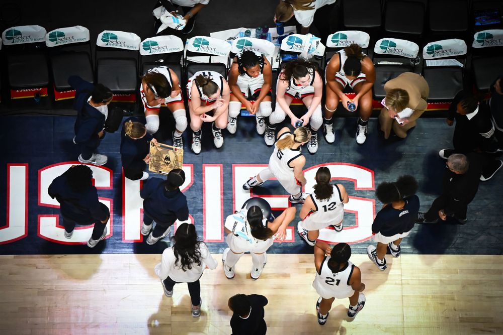 Overhead view of basketball team huddle on court before game.