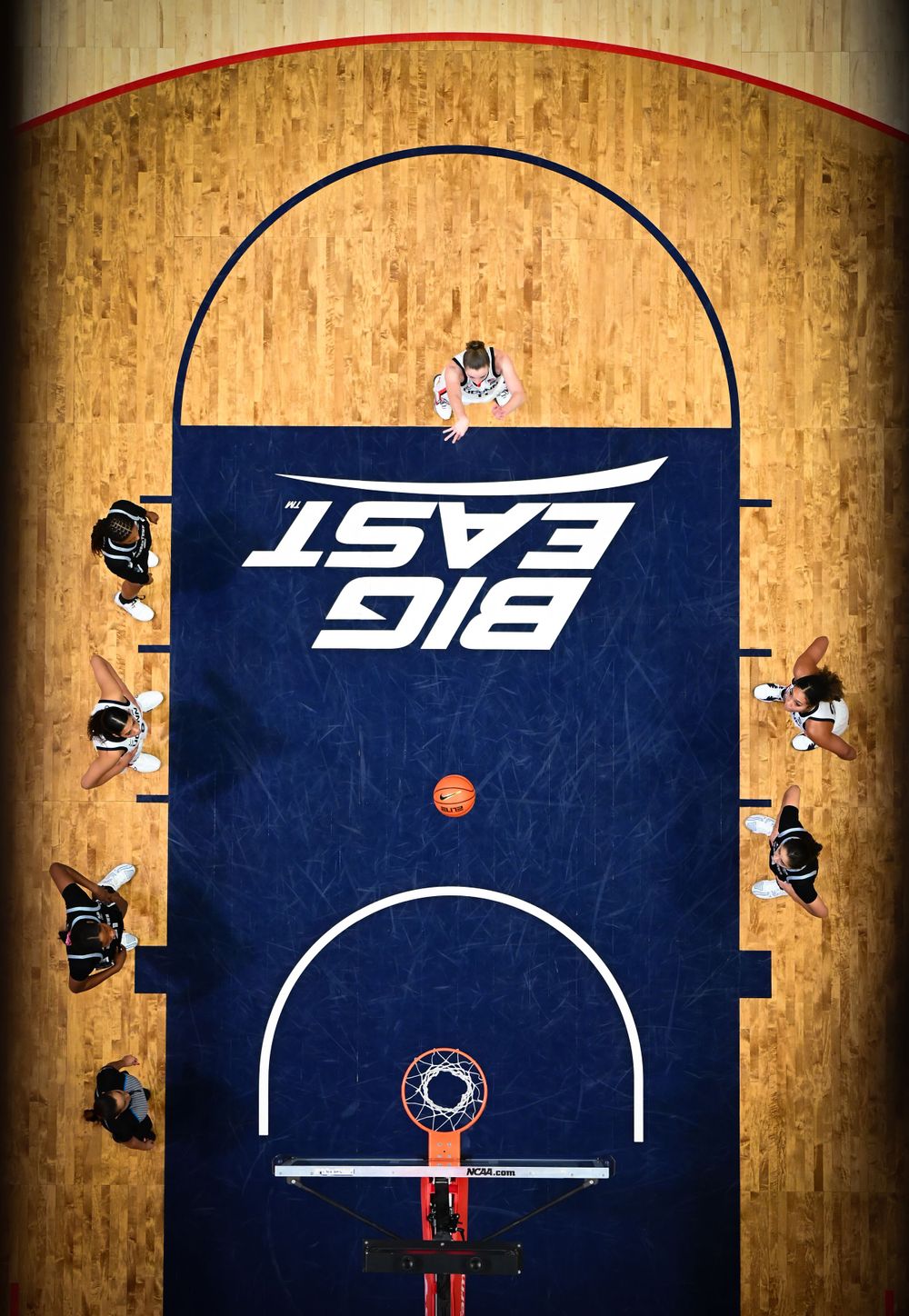 Aerial view of basketball court showing Big East logo and players positioned during game.