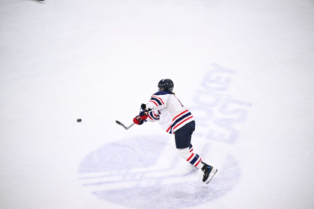 Hockey player takes a shot on ice during competitive match.