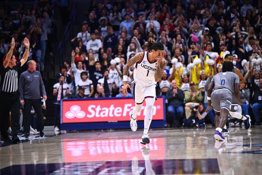 Basketball player dribbles during intense game action with crowd in background.