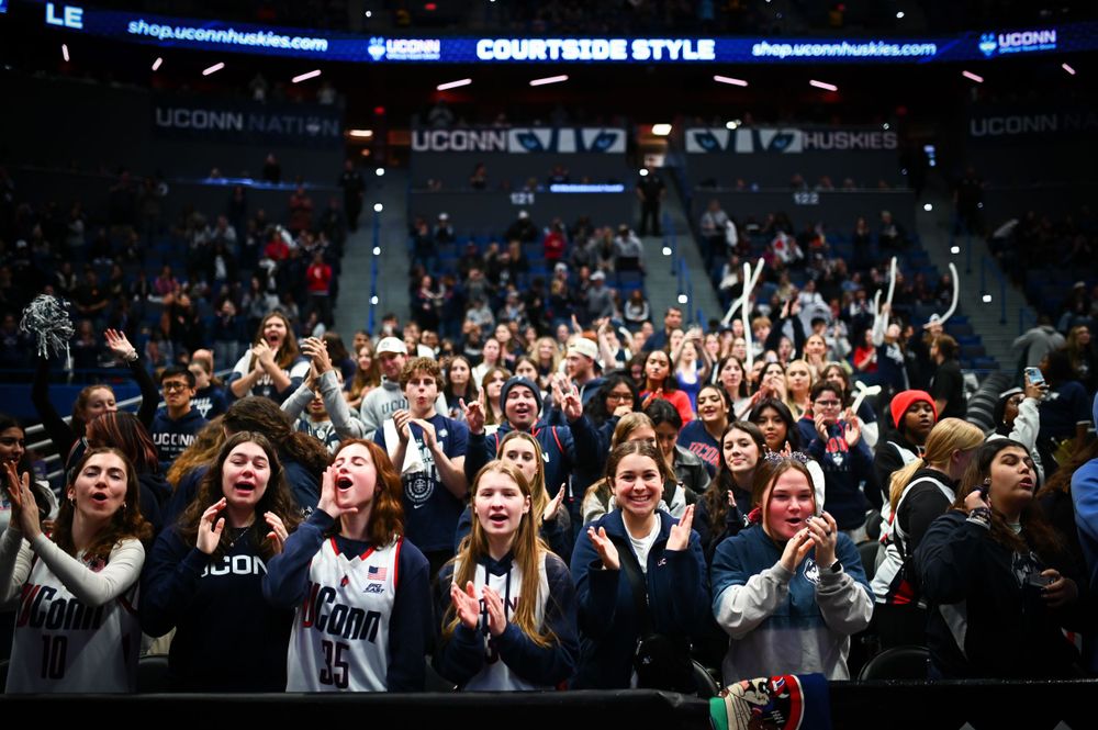 Enthusiastic crowd cheers in a packed indoor arena during a sports event.