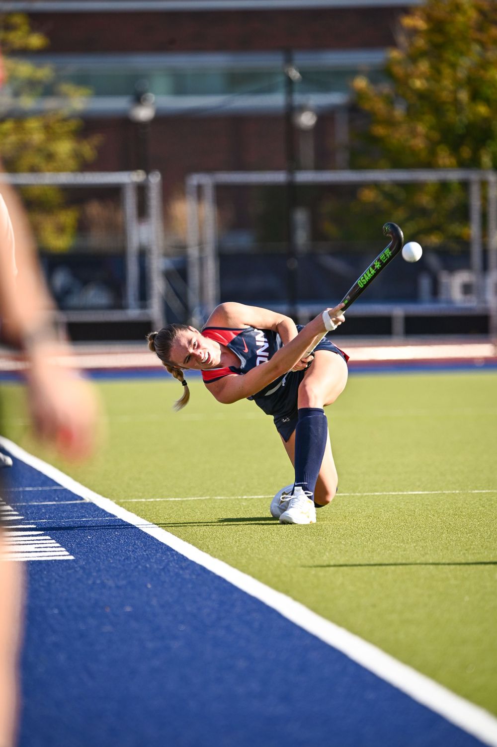 Field hockey player takes a low shot on the artificial turf field.