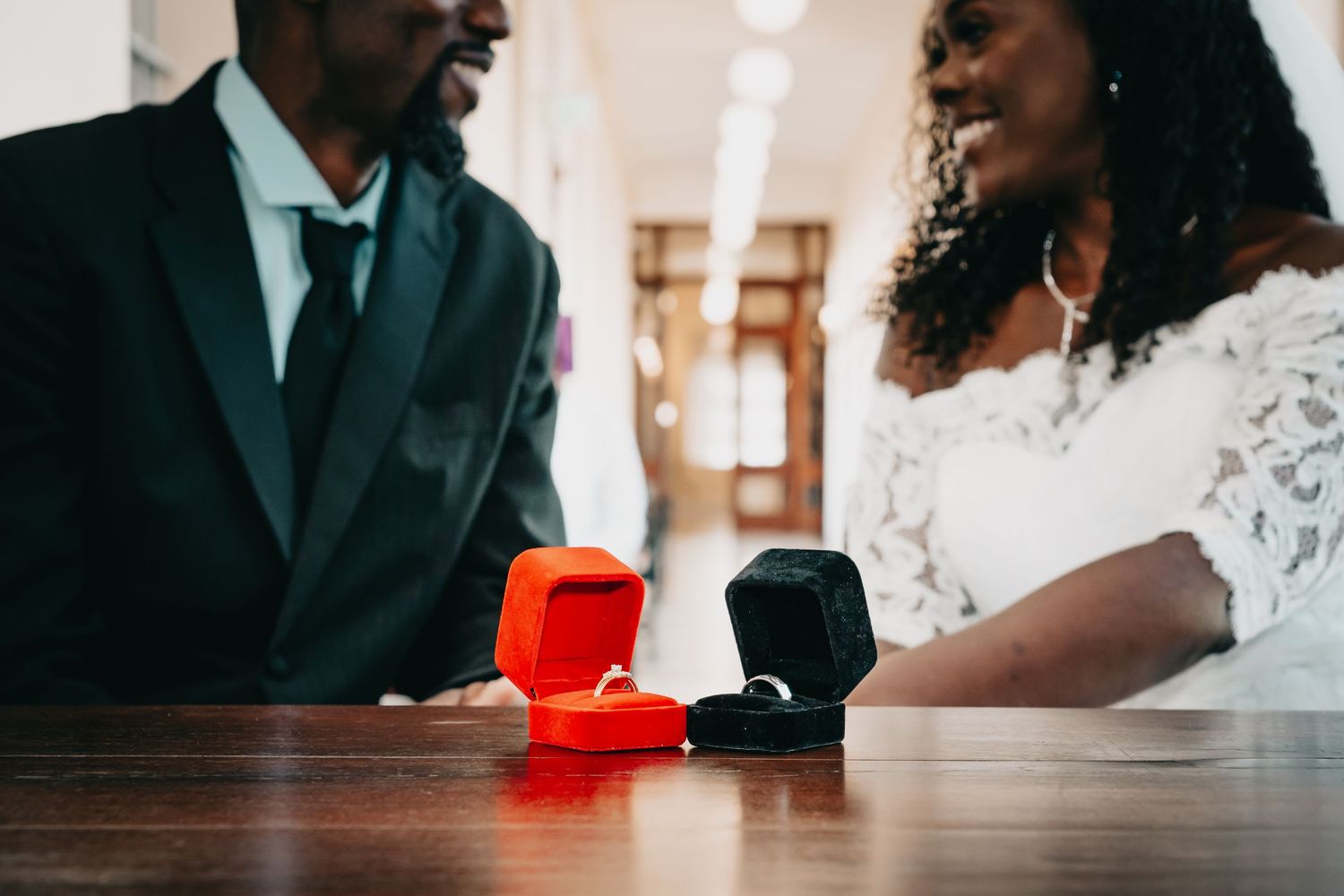 Wedding rings displayed in red and black boxes on a wooden table.