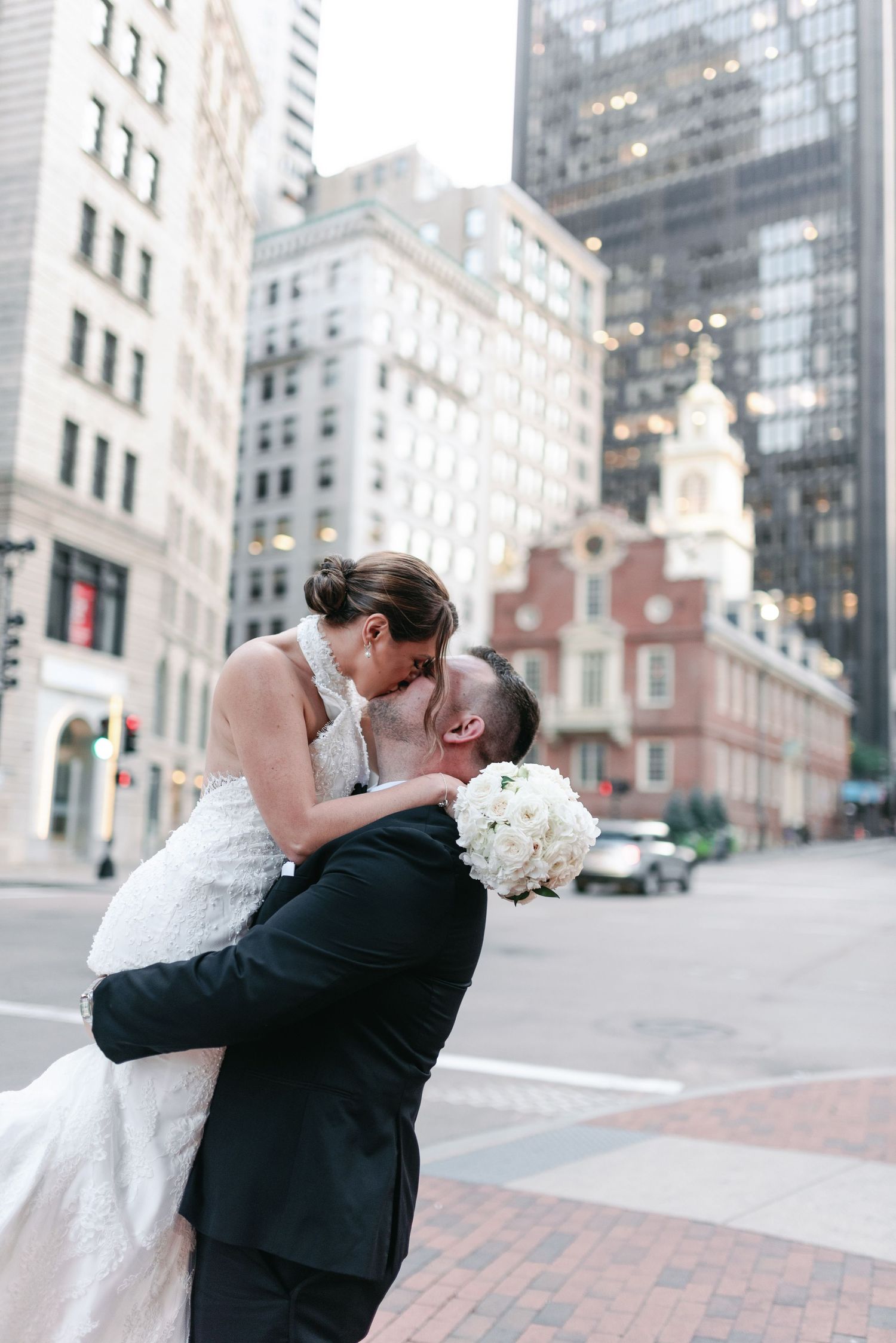 A romantic dip kiss moment between newlyweds against Boston's historic architecture.