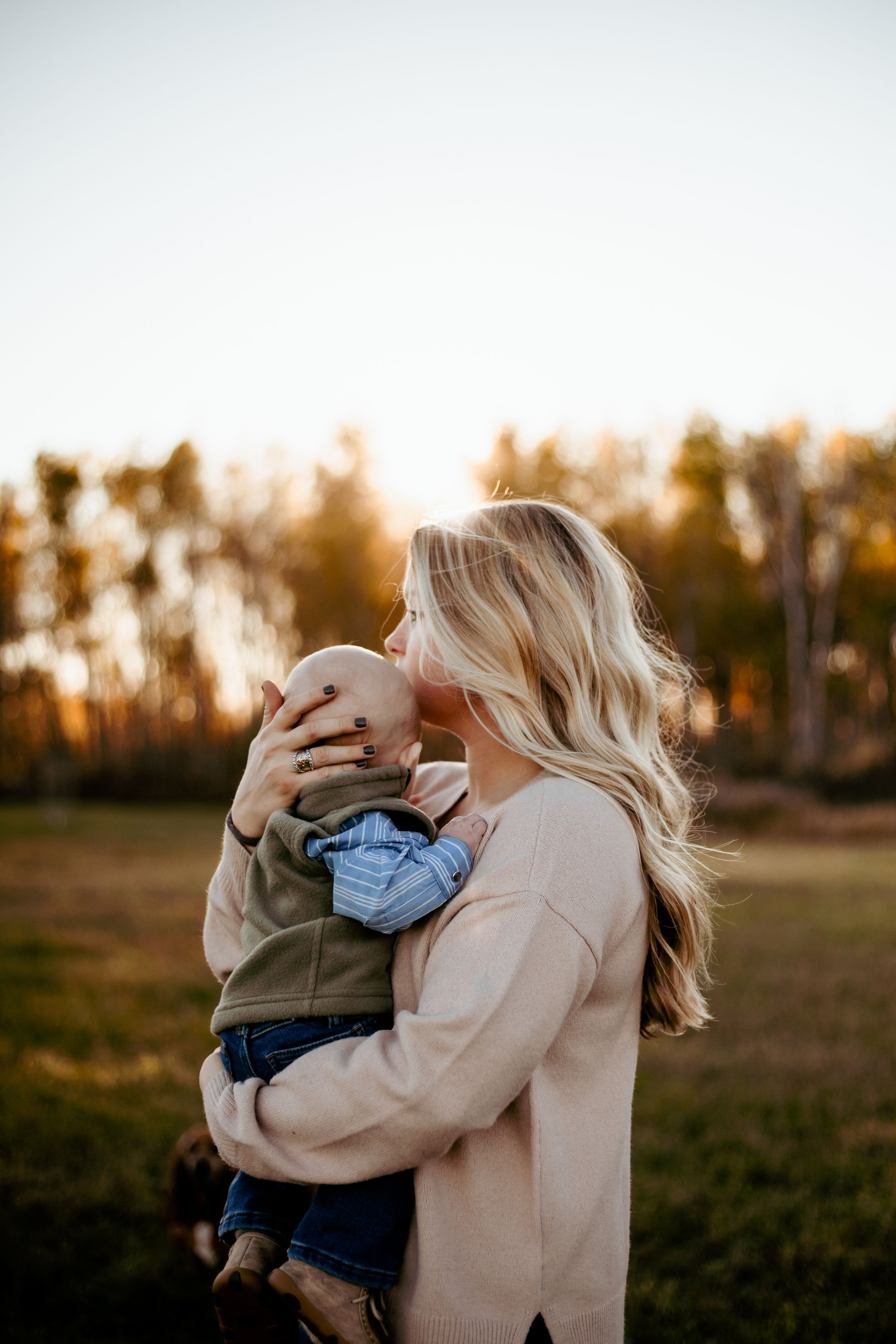A parent and child share a tender moment in a golden field at sunset, creating a warm and intimate silhouette.