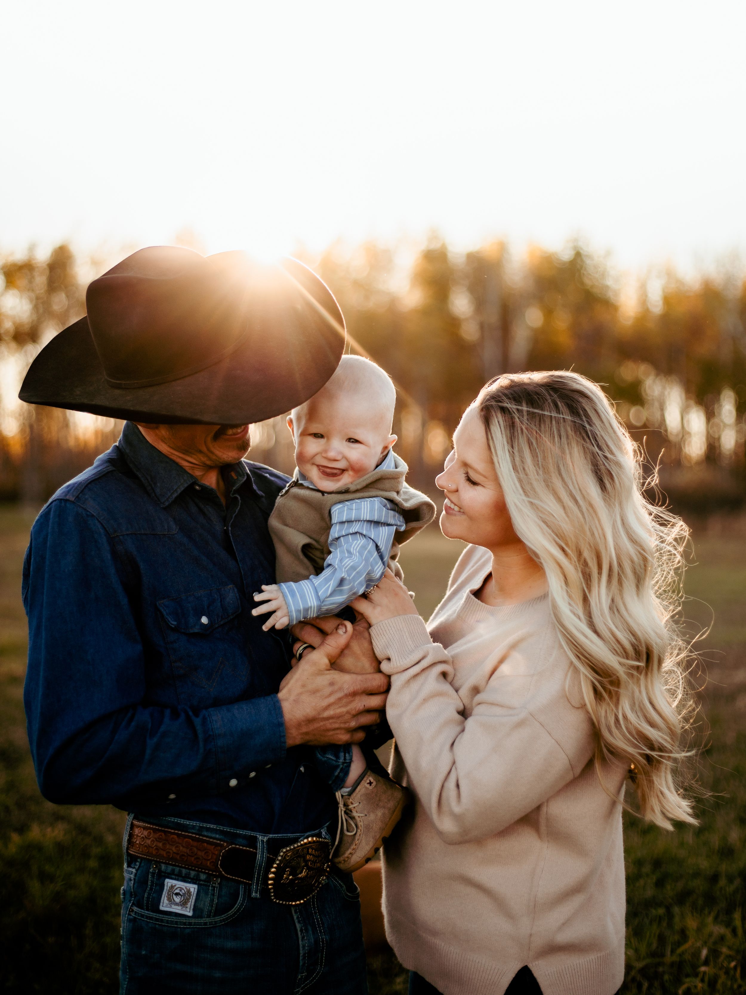 Family embraces during golden hour photography session wearing coordinated casual western outfits.