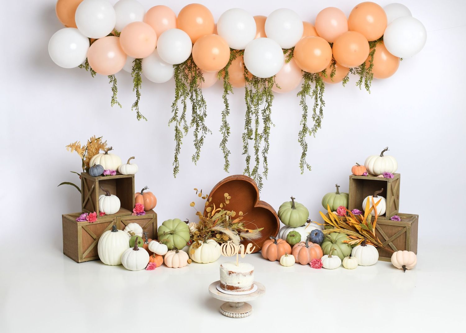 Boho neutral first birthday setup with peach, cream, and tan balloon garland.