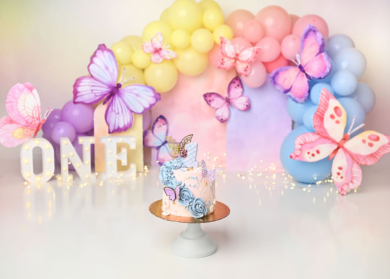 Pastel Butterflies themed first birthday cake smash setup with colorful balloons in Linden, New Jersey.