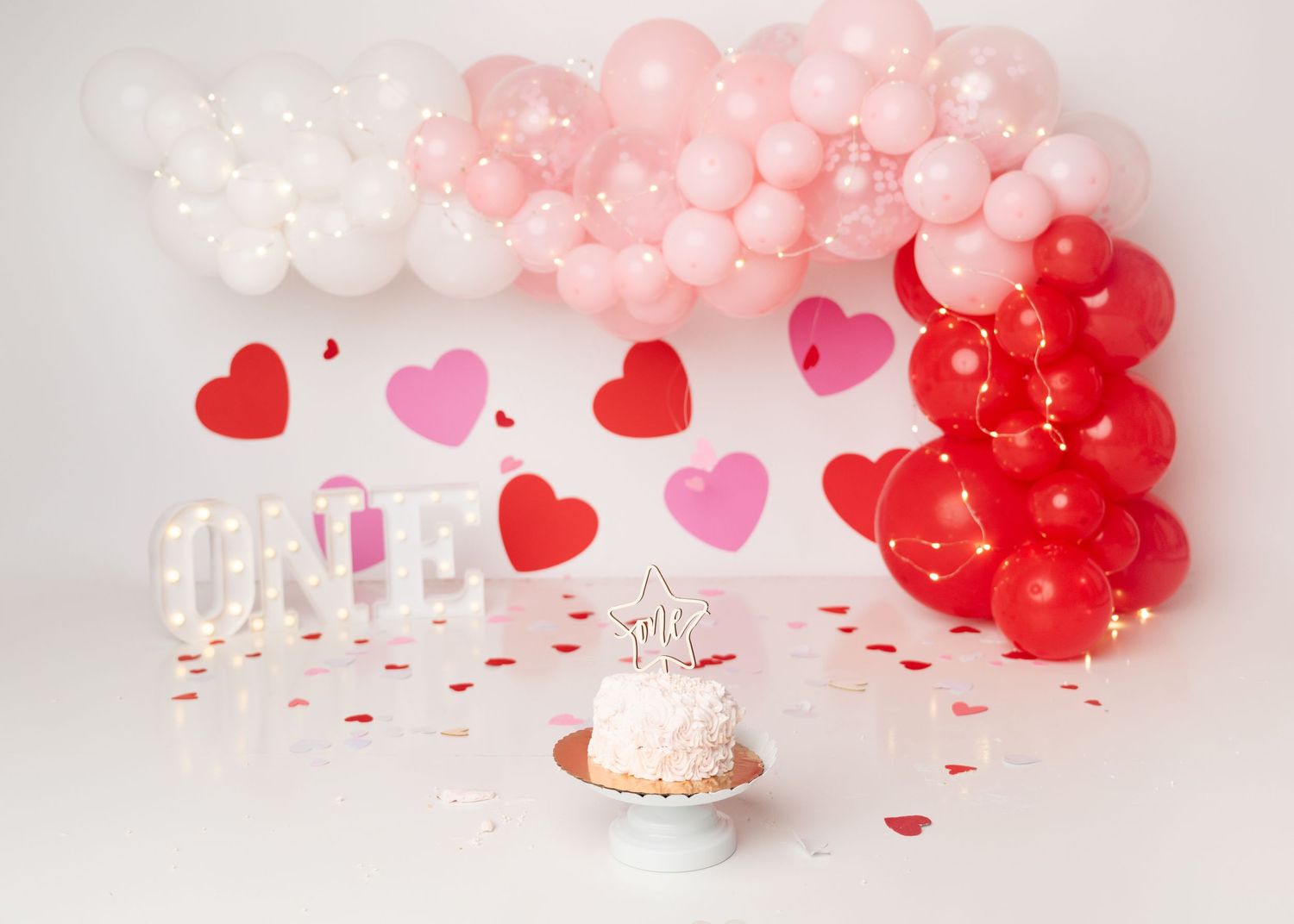 Pink and red heart themed first birthday cake smash setup in Linden, New Jersey.