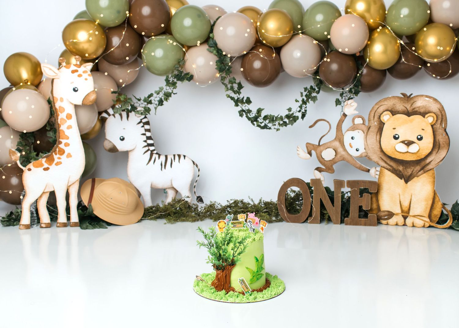 Jungle lion first birthday cake smash setup with green and brown balloons in Linden, New Jersey.