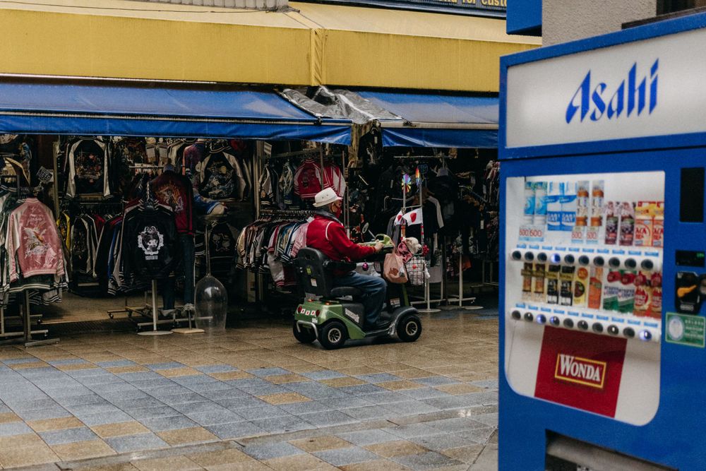 A vending machine and clothing shop storefront on a rainy Japanese street.