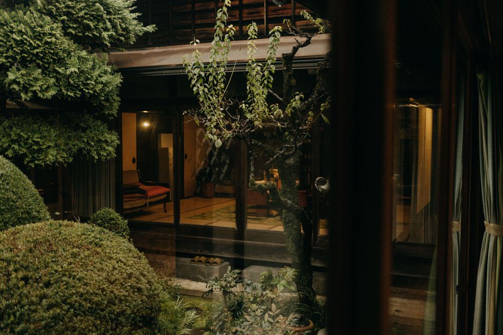 Traditional Japanese garden walkway with wooden architecture and landscaping at dusk.