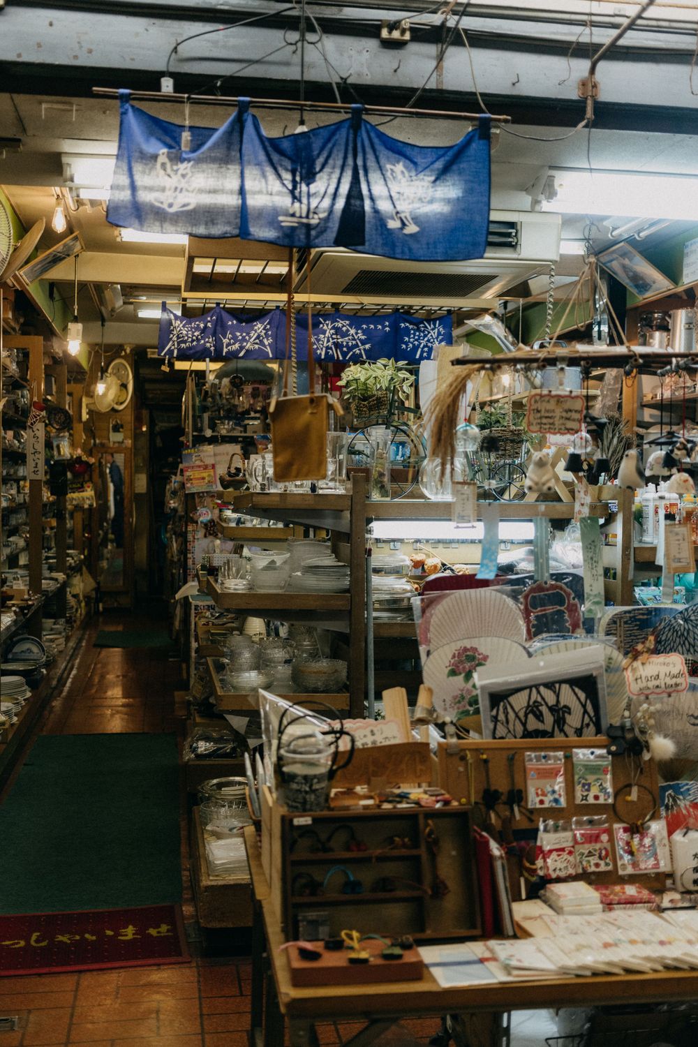 Cluttered antique shop interior with blue banners hanging from ceiling.