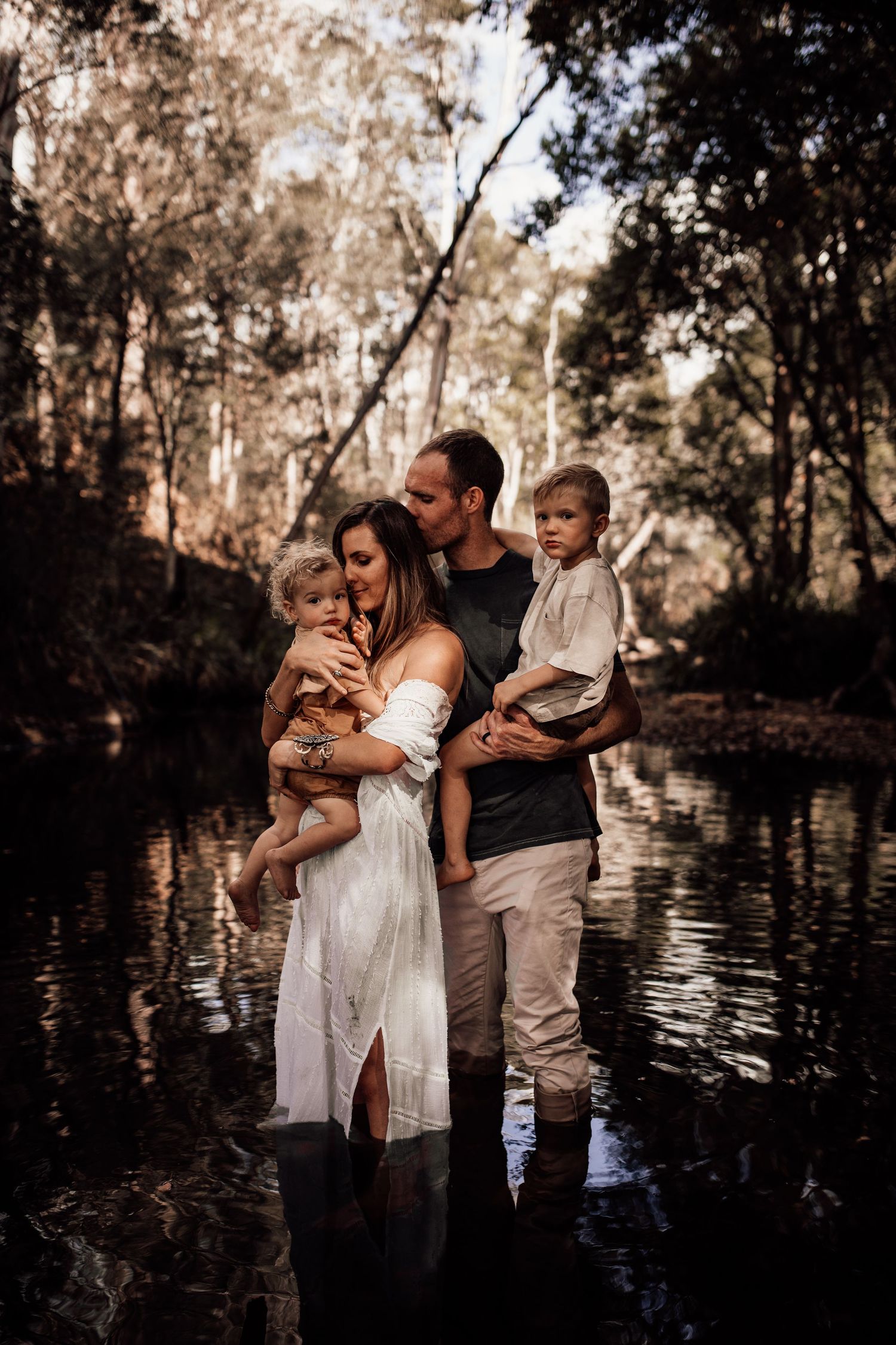 A family stands together in shallow water during an intimate outdoor photo session.