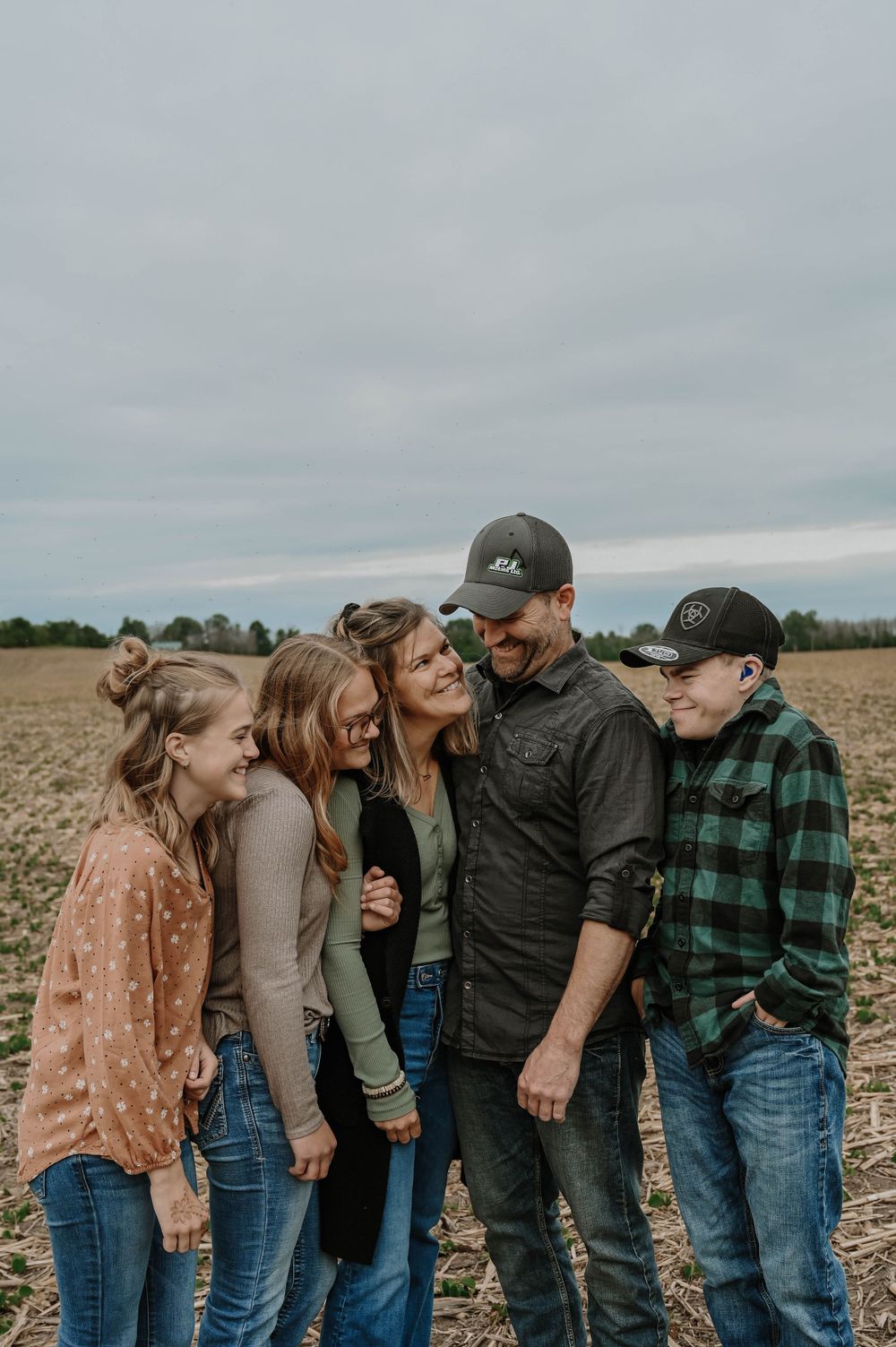 Group sharing a candid moment together while standing in an open field on an overcast day.