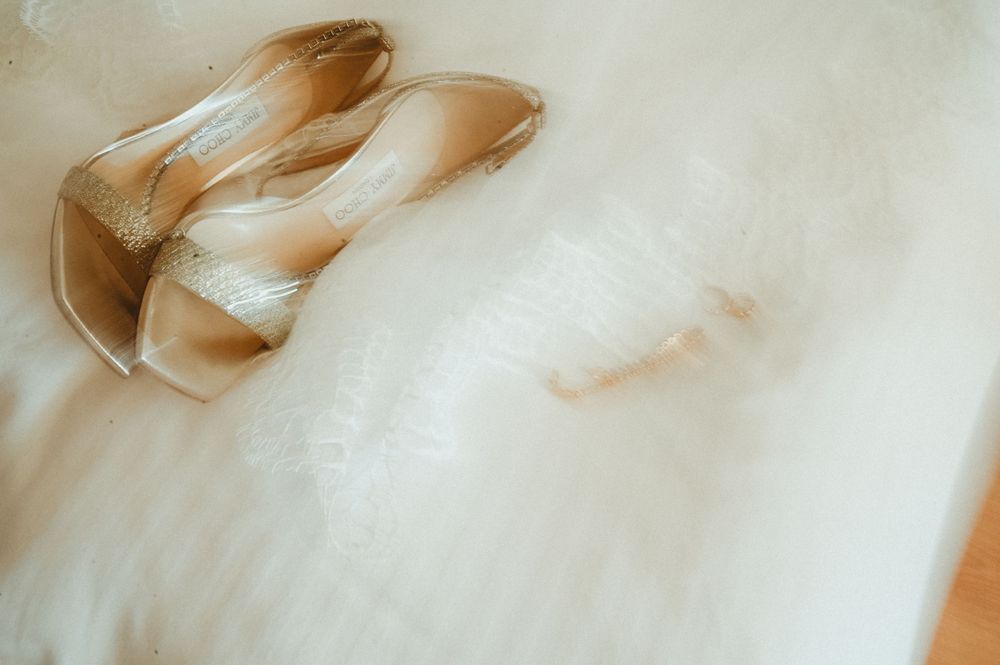 Elegant beige bridal shoes resting on soft white tulle fabric with romantic lighting.