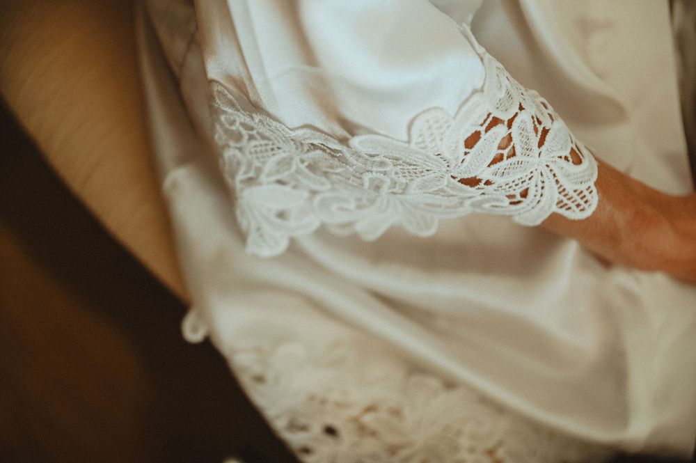 Close-up detail of delicate white lace trim on satin fabric from a wedding dress.