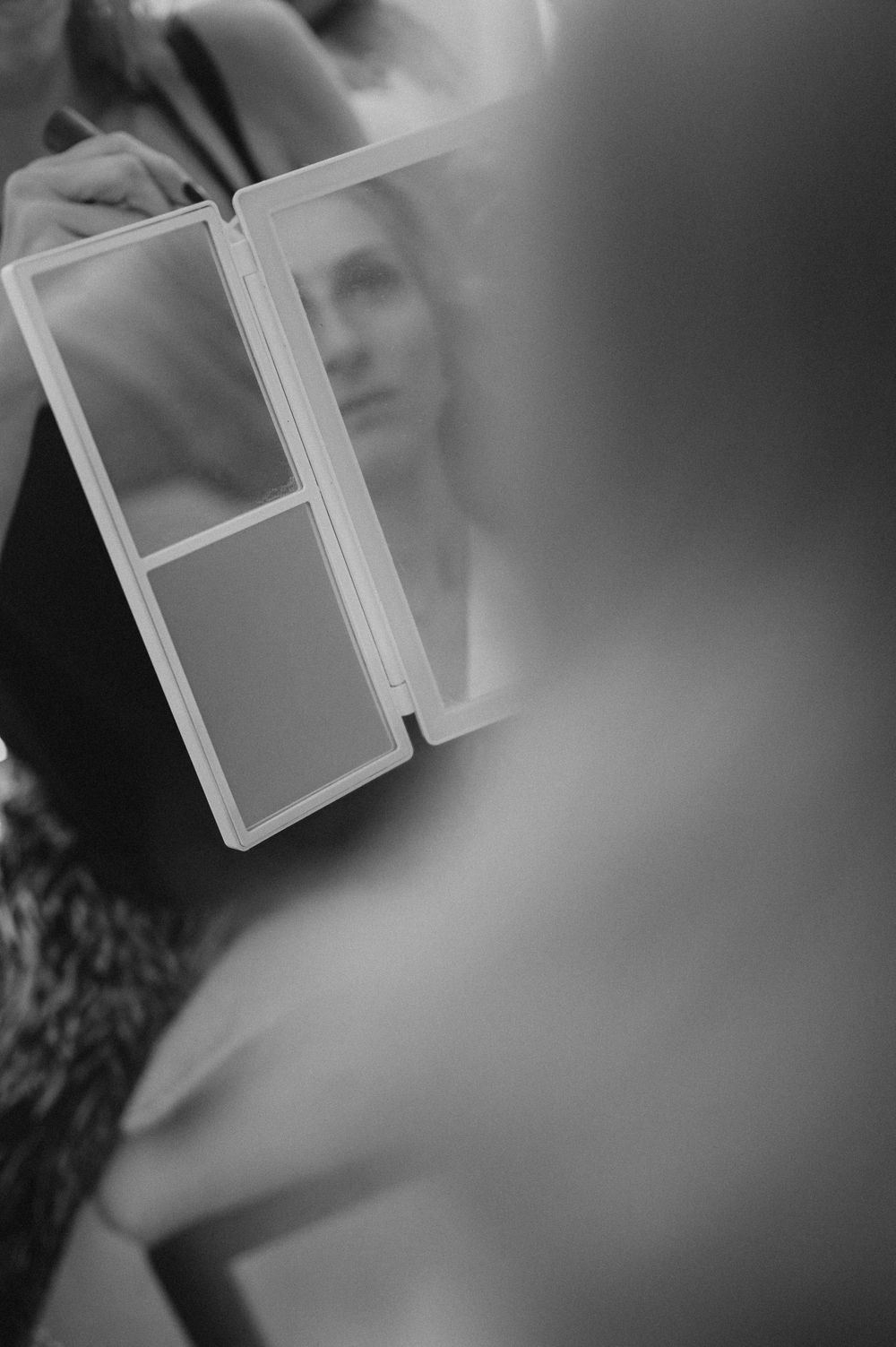 A blurry black and white photograph showing a window frame with a soft, ethereal reflection against a dark background.