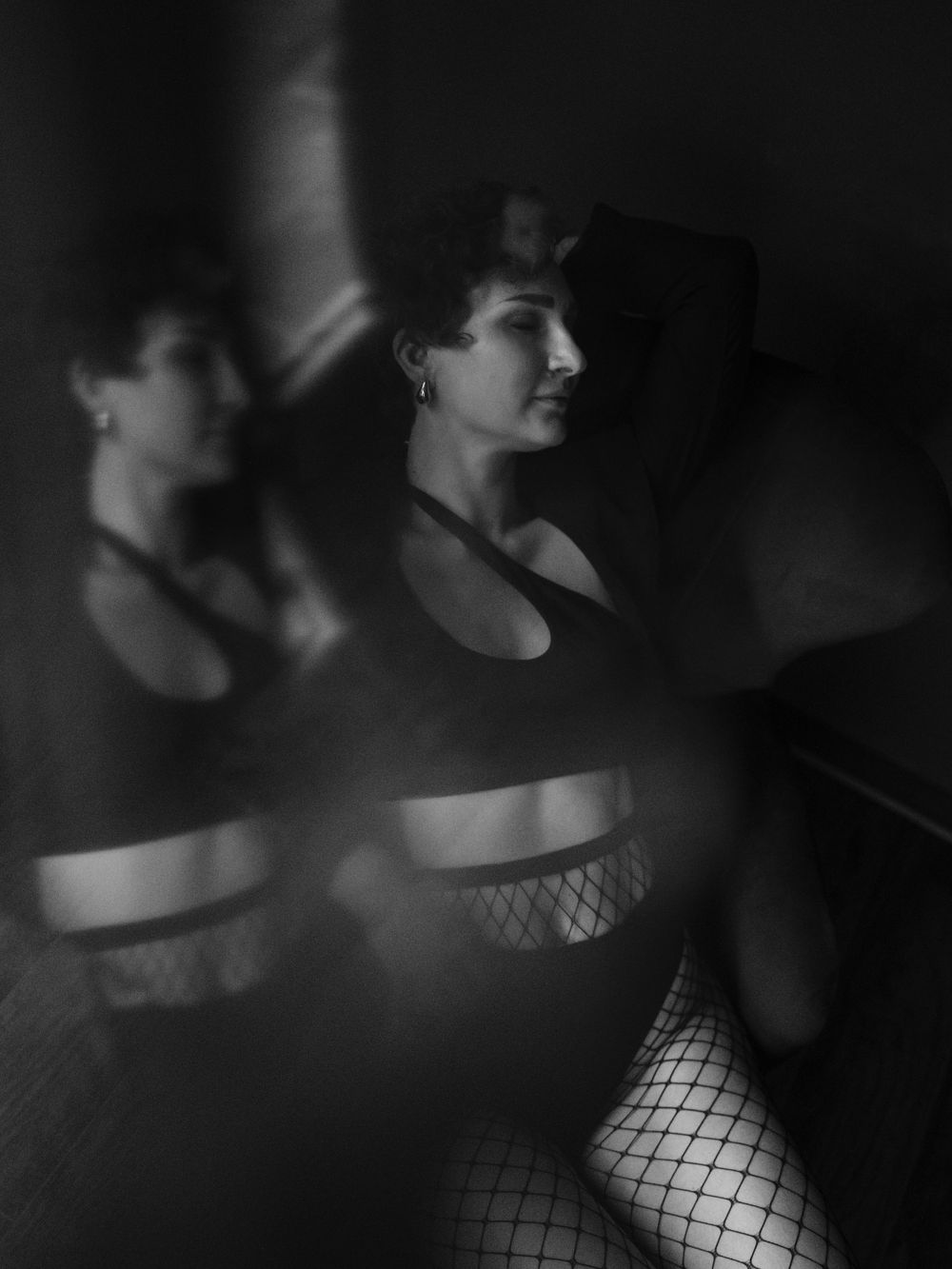 Dramatic black and white artistic portrait with shadows, reflections and fishnet details creating a moody aesthetic  in Bellevue studio..