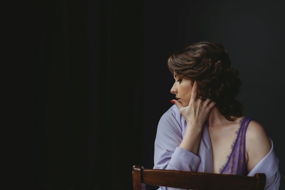 Moody boudoir portrait in purple tones with dramatic lighting. Bellevue studio, WA
