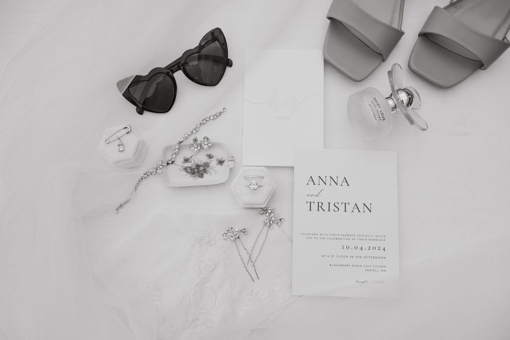 Wedding accessories including sunglasses, invitation card, and jewelry arranged in a flat lay composition.