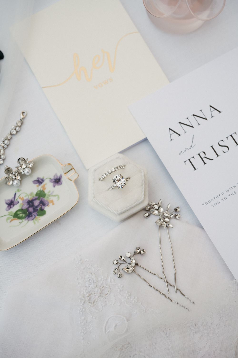 Elegant bridal hair accessories and wedding invitation suite with delicate florals and gold calligraphy against white backdrop.