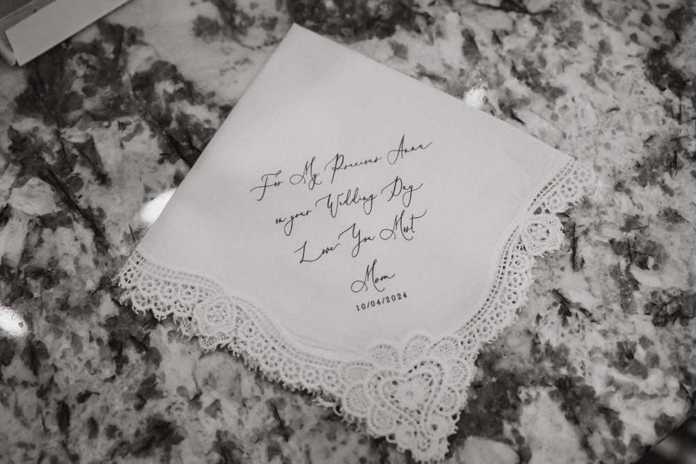 Decorative lace-edged handkerchief with handwritten text lying on a marbled surface.