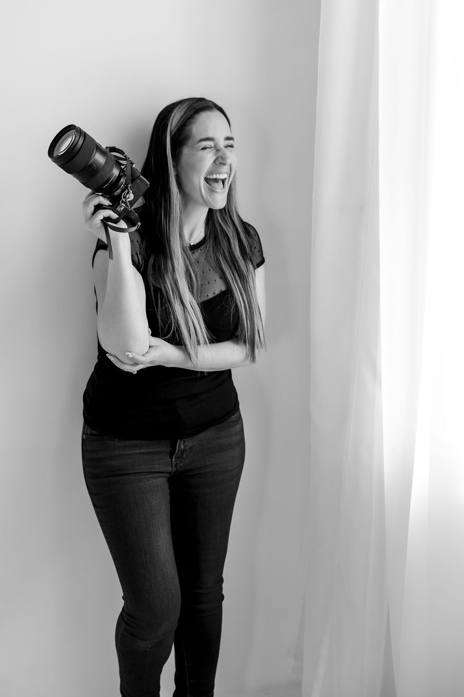Smiling photographer holding her camera during a studio branding session in Central Indiana.