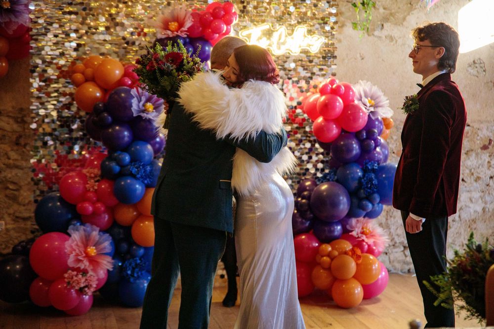 Wedding celebration with colorful balloon arch and confetti.
