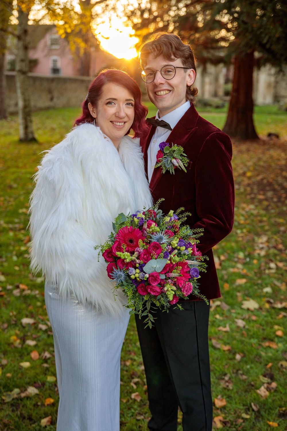 Sunset wedding portrait with couple in white fur coat and burgundy velvet jacket.